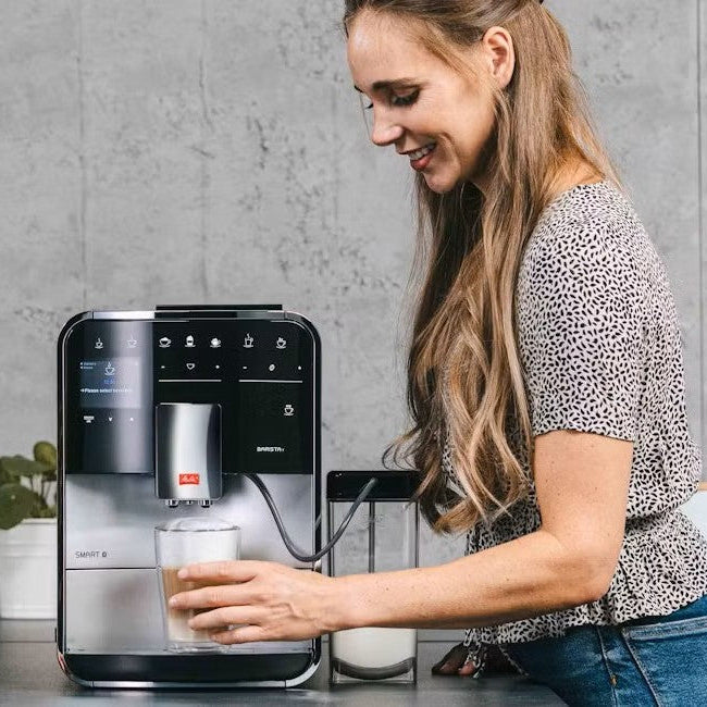 Man and woman using a coffee machine in a modern kitchen.
