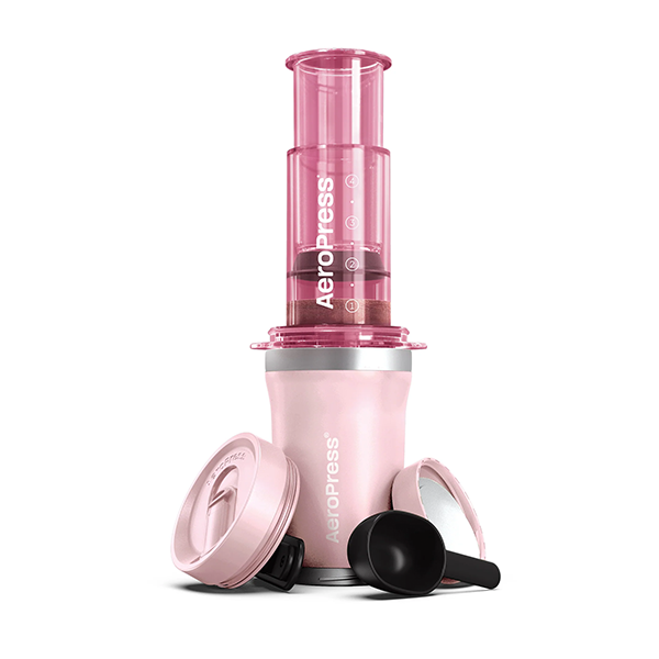 Pink AeroPress coffee maker on a white background