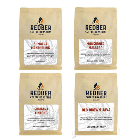 Four bags of coffee from the Asian Coffee Taster Pack by REDBER coffee roasters, each bag labeled with different coffee varieties: Sumatra Mandheling, Monsooned Malabar, Sumatra Lintong G1, and Old Brown Java.