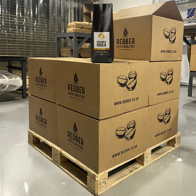 Stack of Redber Coffee Roasters boxes with a coffee bag on a pallet in a warehouse.