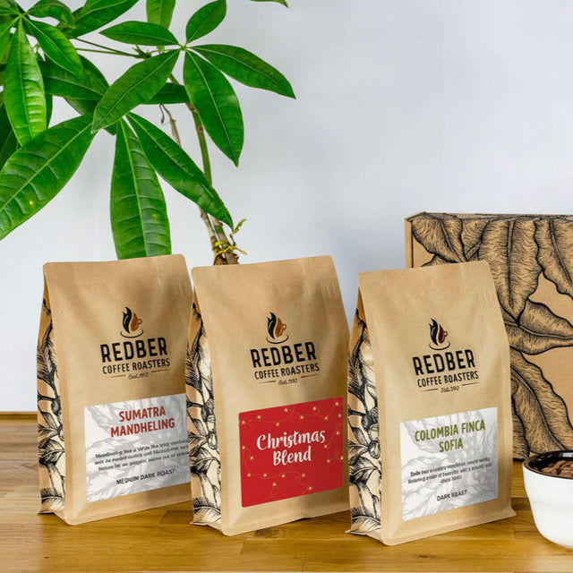 Redber Coffee Roasters packages on a wooden surface with a plant in the background