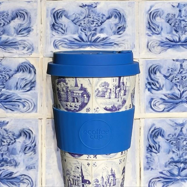 Blue and white patterned travel mug with blue lid on a tiled wall background
