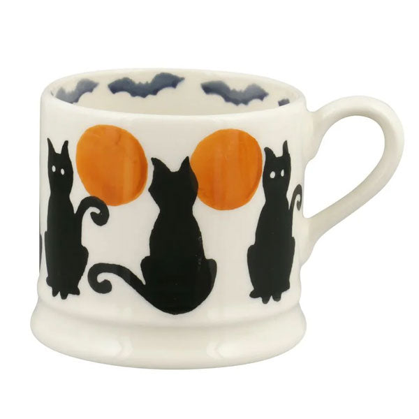 White mug with black cats and orange circles on a white background