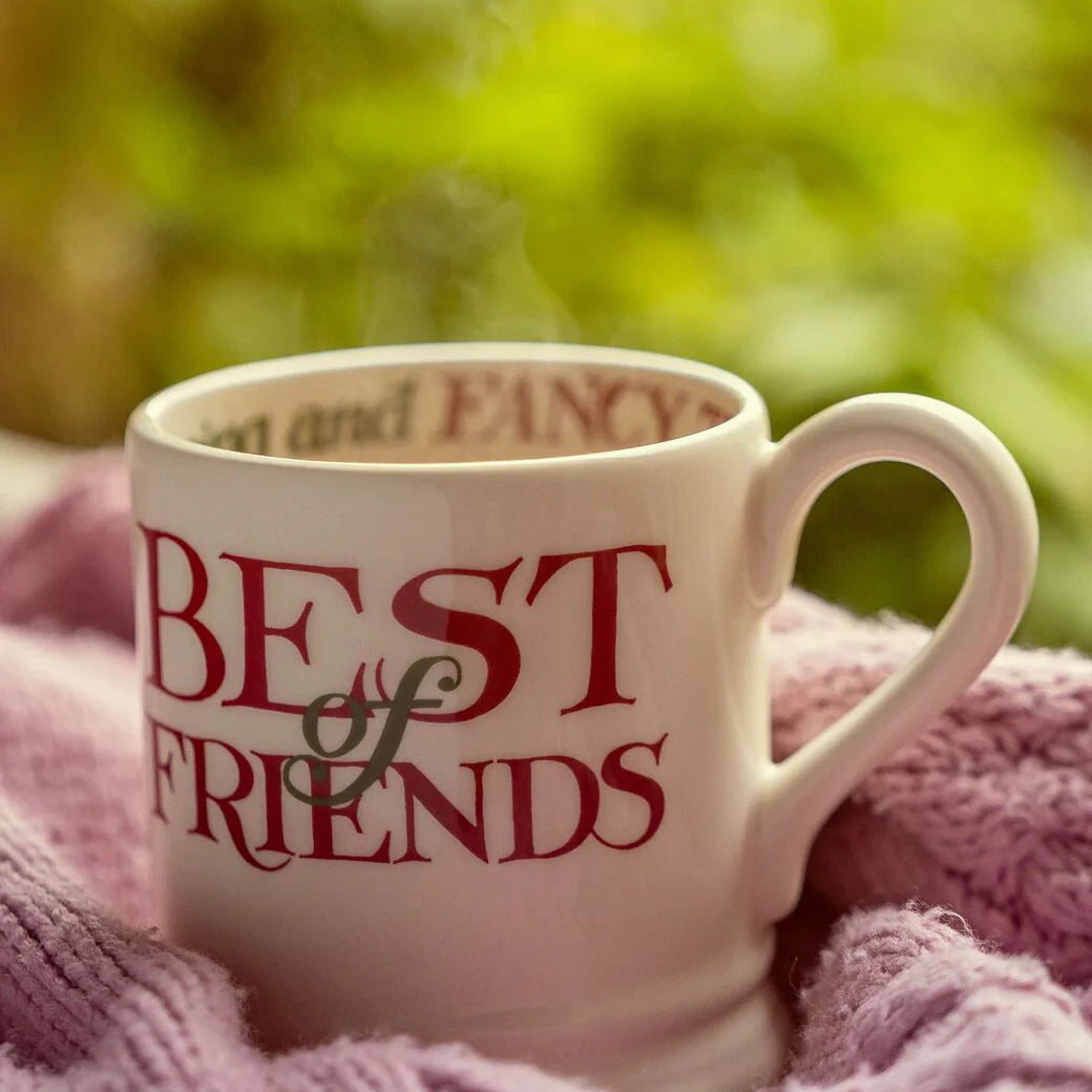 White mug with 'Best Friends' text on a pink blanket with a blurred green background