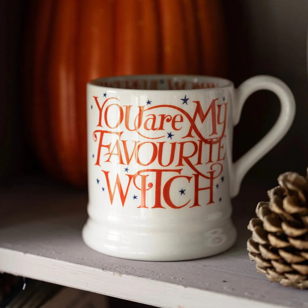White mug with red text 'You are my favourite witch' on a shelf with a pumpkin and pine cone in the background.