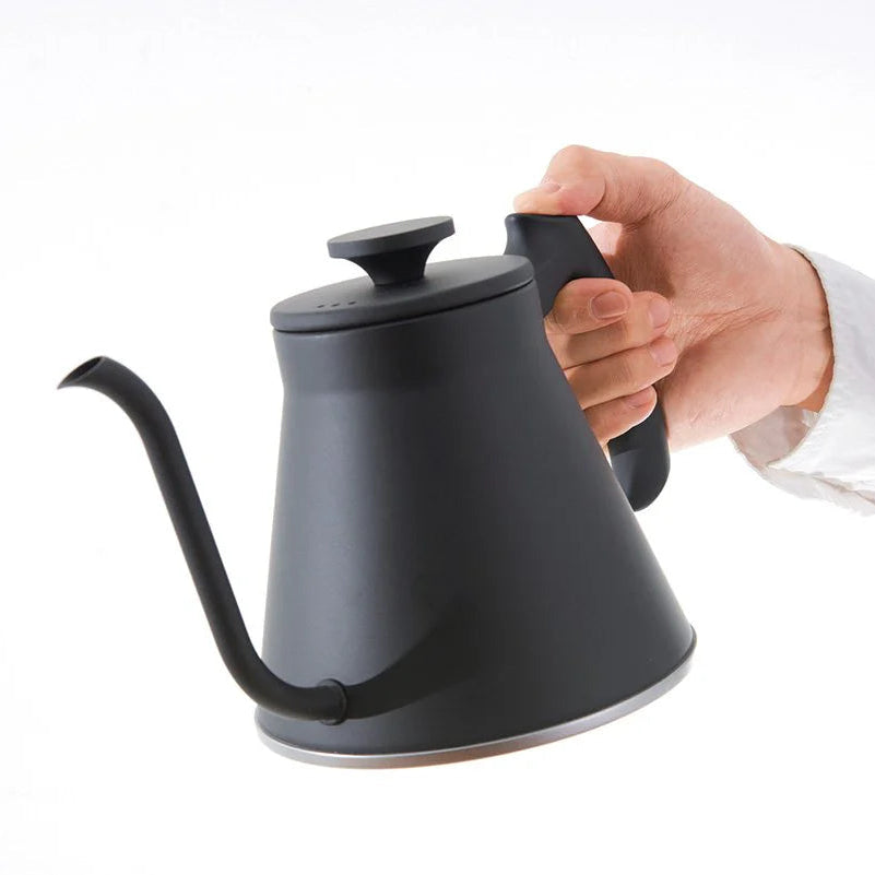 Person holding a black kettle against a white background