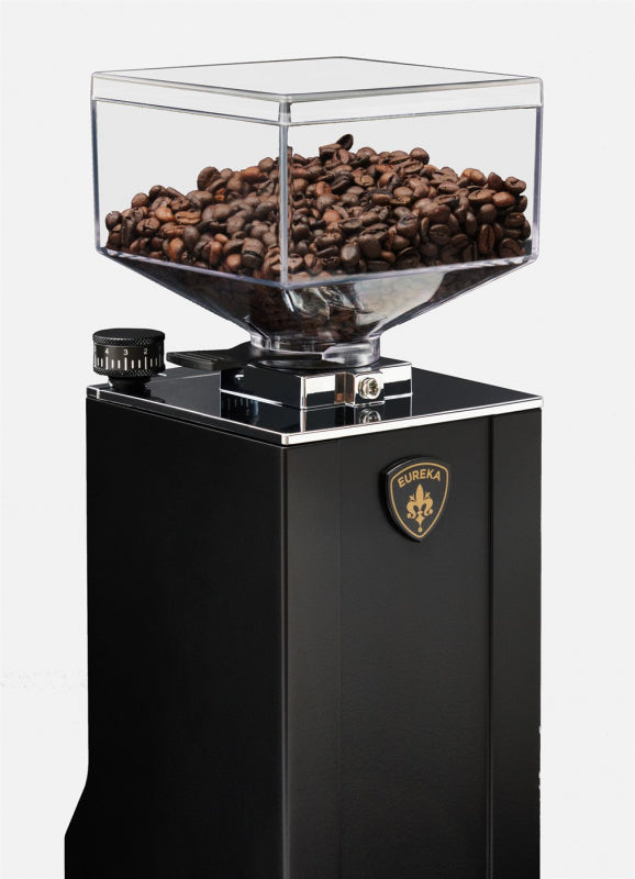 Black coffee grinder with clear container filled with coffee beans on a white background