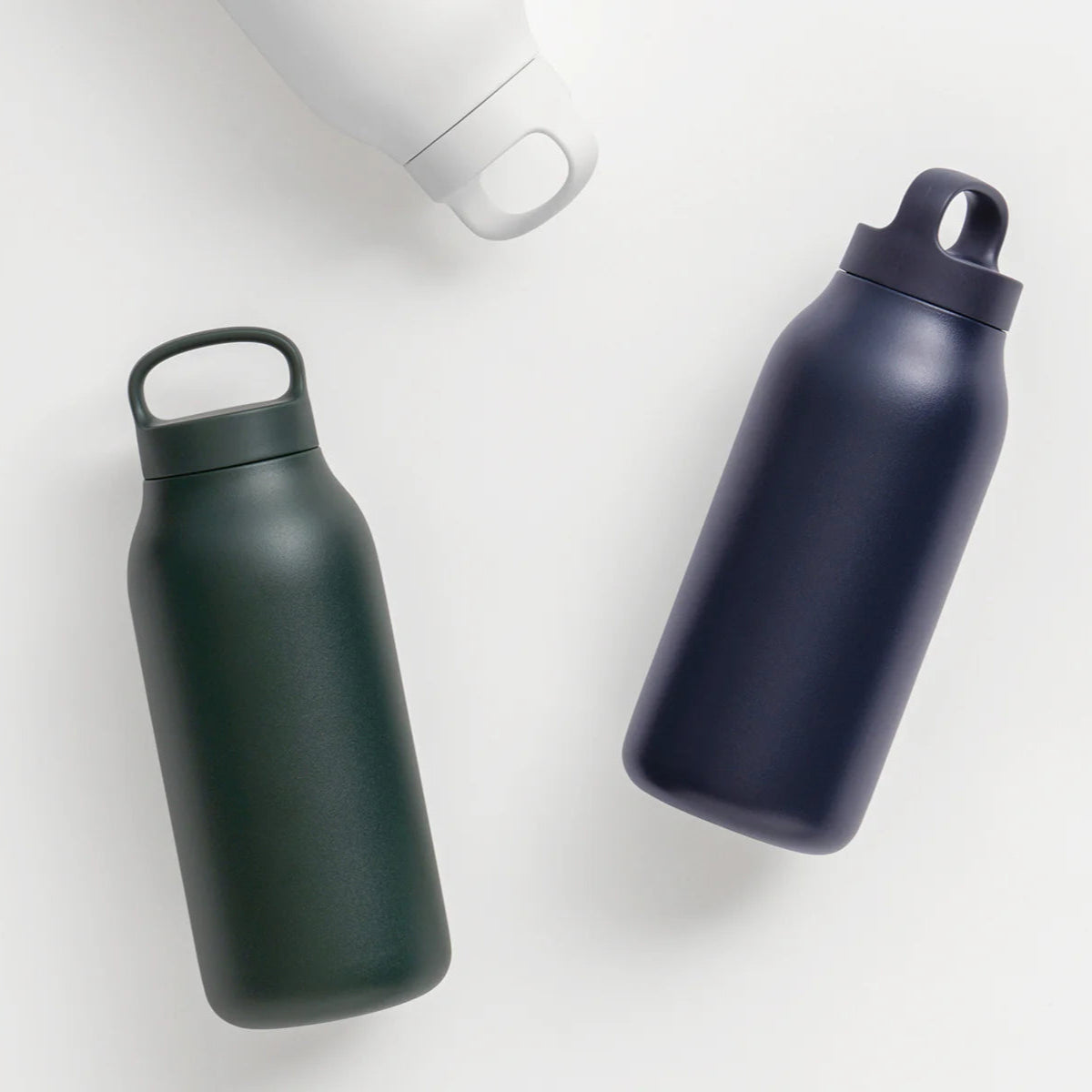 Three insulated water bottles in different colors on a light background