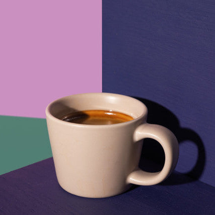 Beige mug with coffee on a multicolored background