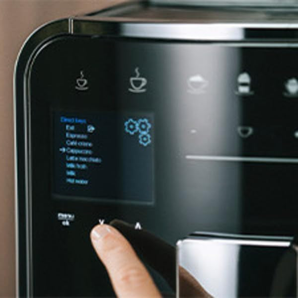 Person pressing a button on a coffee machine with a digital display.