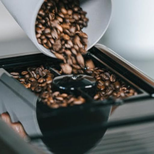 Coffee beans being poured into a coffee machine.