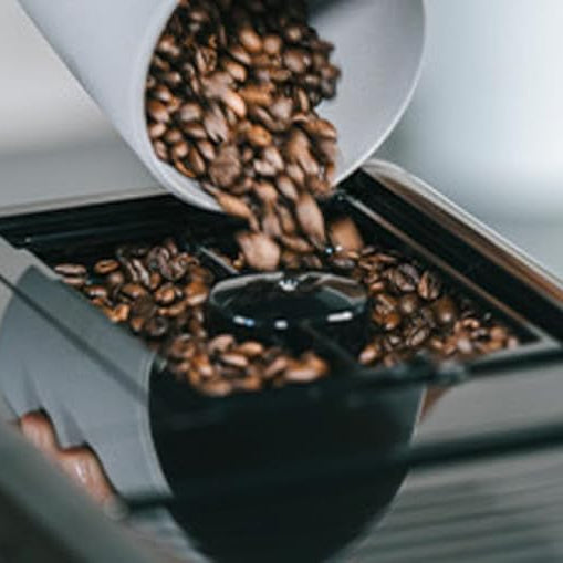 Coffee beans being poured into a coffee machine.