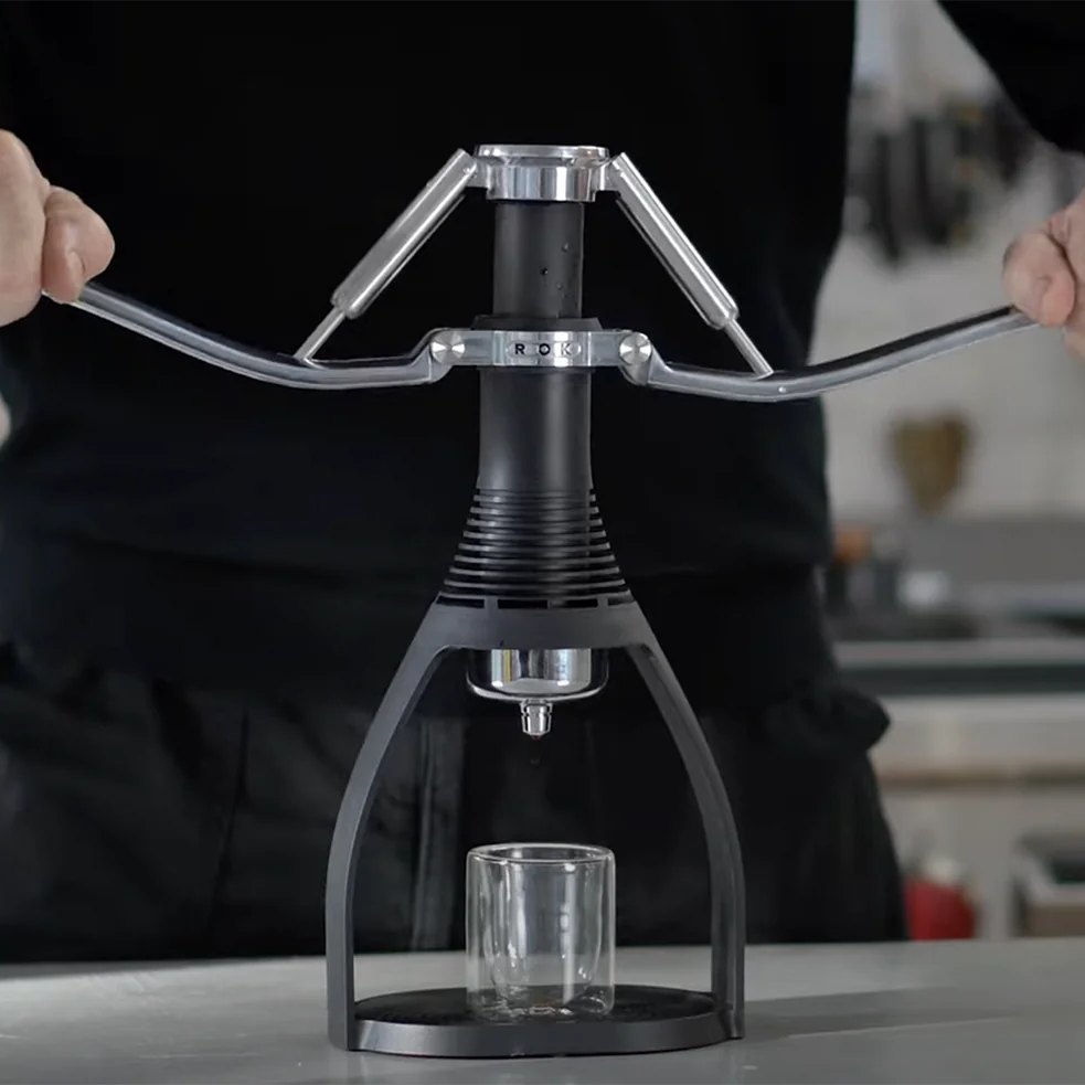 Person using a manual coffee press in a kitchen setting