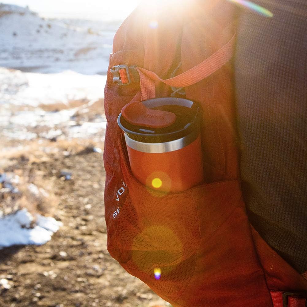Person holding a coffee cup with a backpack outdoors