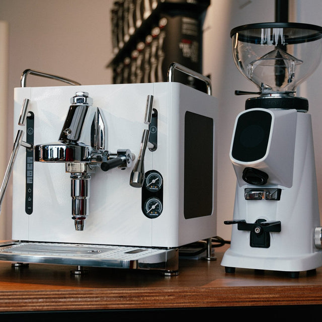 White espresso machine and grinder on a wooden surface