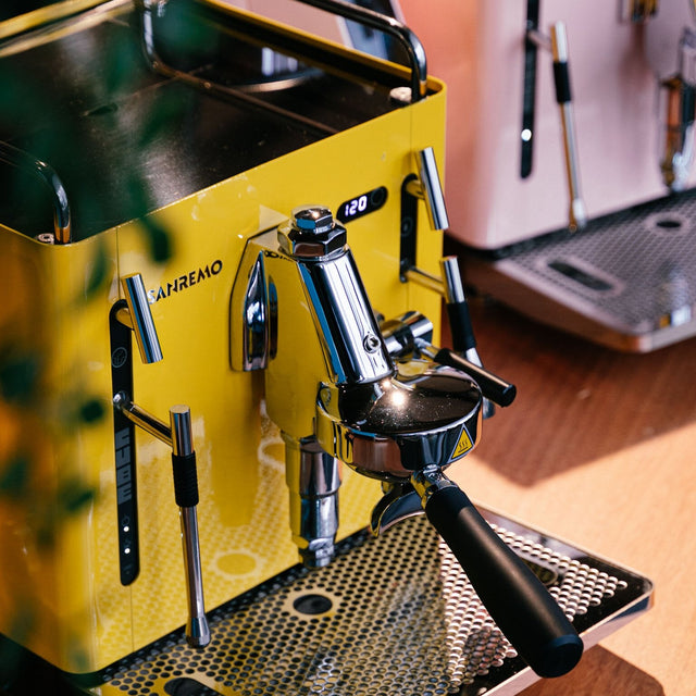 Yellow and black espresso machine on a wooden surface