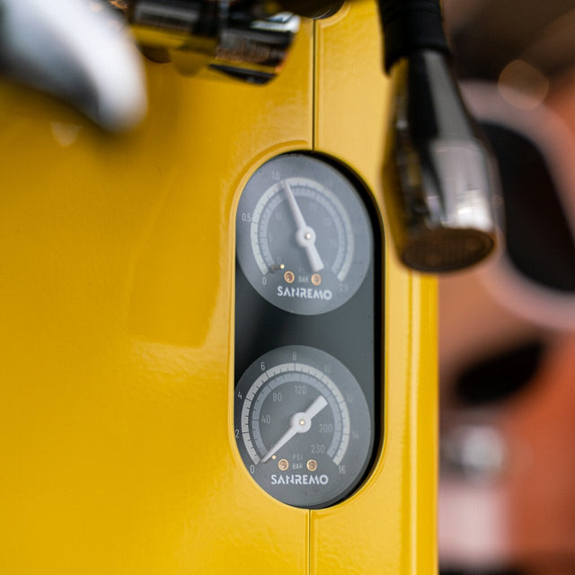 Yellow espresso machine with gauges on a blurred background