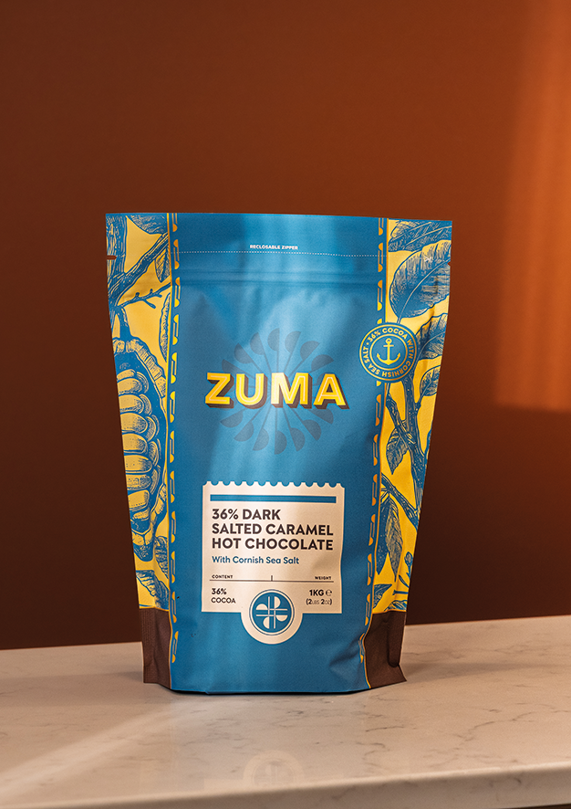 Zuma dark salted caramel hot chocolate packaging on a wooden surface with a brown background