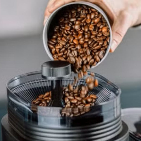 Hand pouring coffee beans into a coffee grinder