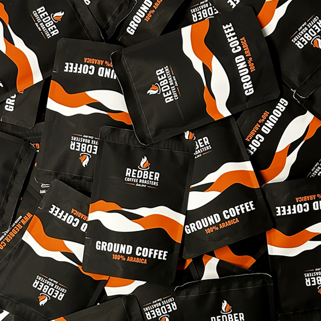 Multiple packages of Redber Coffee Roasters ground coffee with black, orange, and white design.