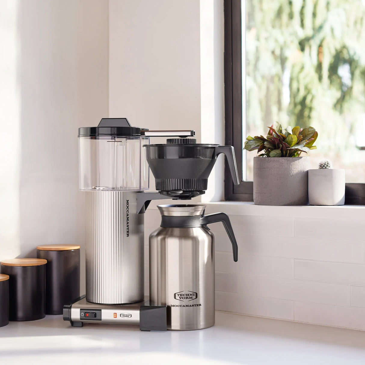 Coffee maker on a kitchen counter with a window in the background