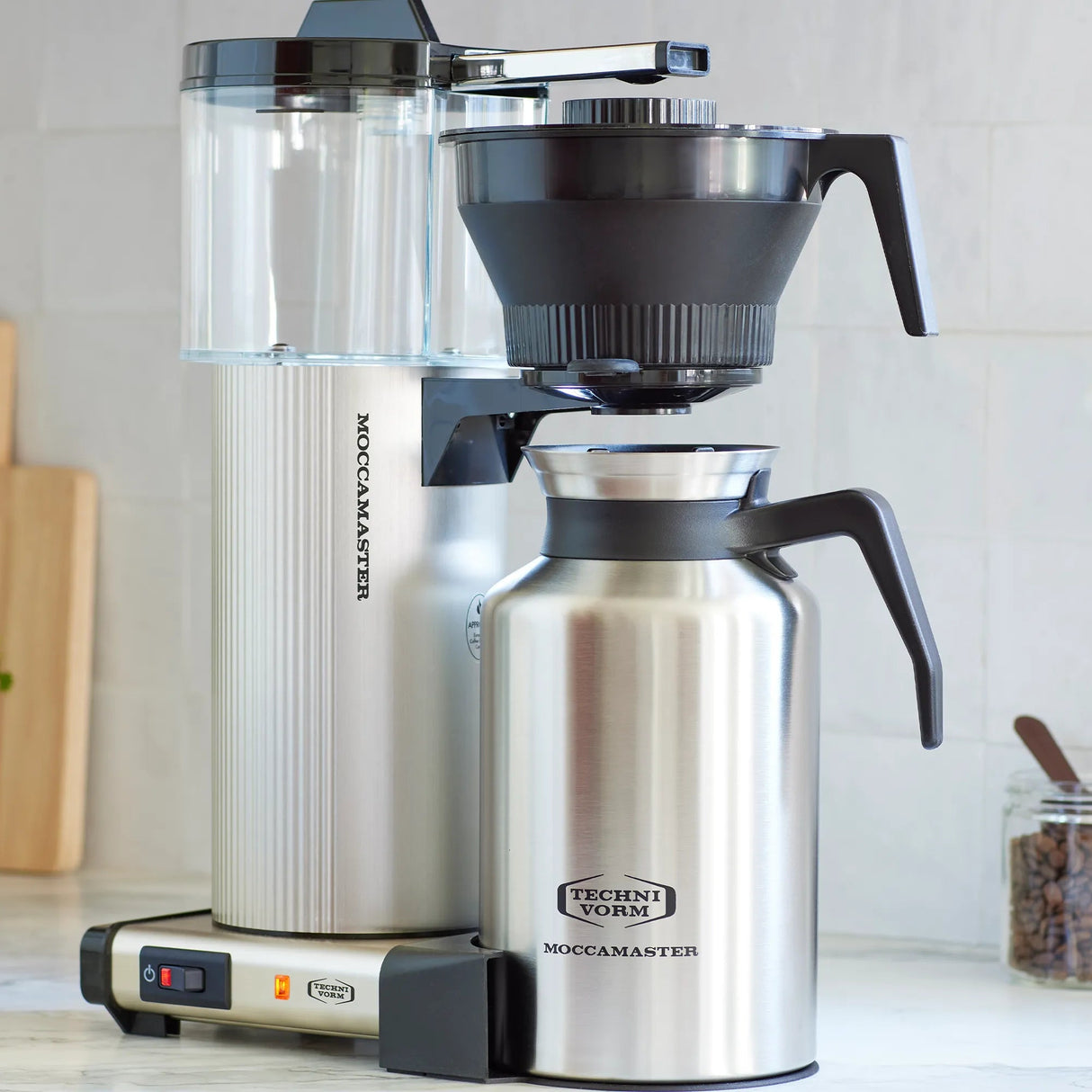 Technivorm Moccamaster coffee maker on a kitchen counter with a thermos.