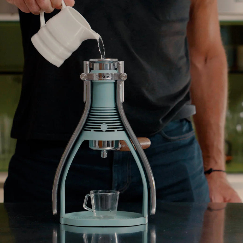 Person using a manual coffee press in a kitchen setting