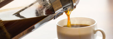 Fresh coffee brewed in a cafetière with roasted coffee beans
