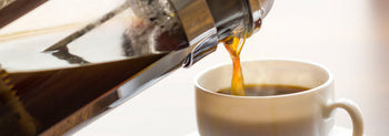 Fresh coffee brewed in a cafetière with roasted coffee beans