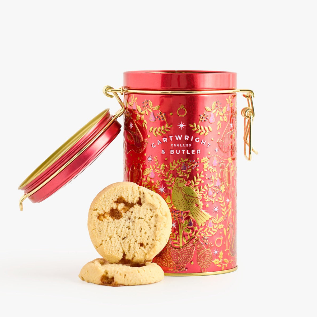 Red decorative cookie tin with gold accents and cookies on a white background