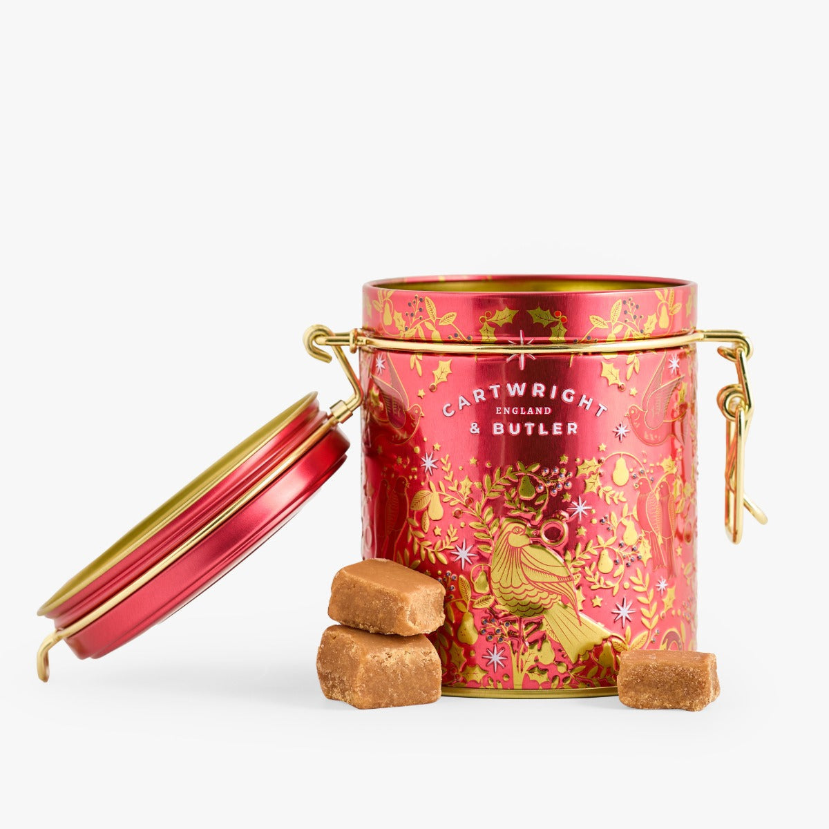 Decorative red tin with gold accents containing taffy on a white background