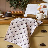 Sophie Allport Christmas Puddings tea towel draped over a kitchen worktop beside festive baking