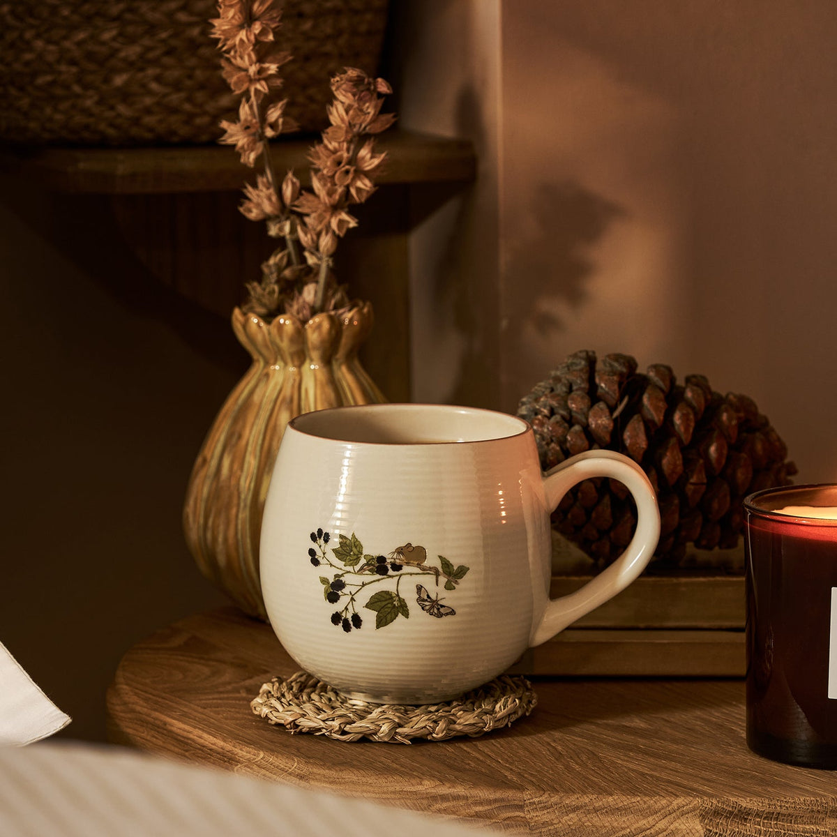Sophie Allport Autumn Forage mug styled with dried flowers, pine cones and a candle