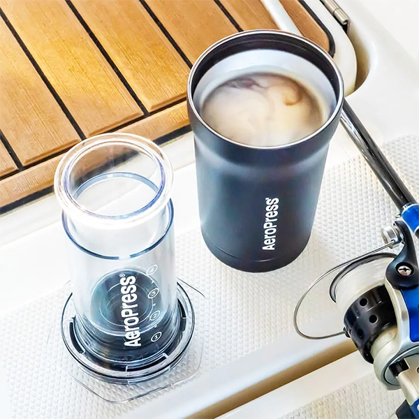 Aeropress coffee maker and a cup of coffee on a wooden deck.