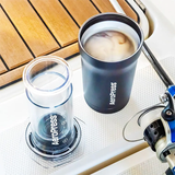 Aeropress coffee maker and a cup of coffee on a wooden deck.