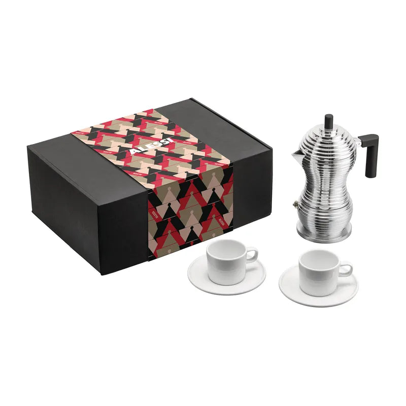 The image shows a coffee gift box from Alessi, containing a silver-colored Pulcina Espresso Coffee Maker and two white mocha cups with saucers. The box is black with a patterned decoration on the lid.