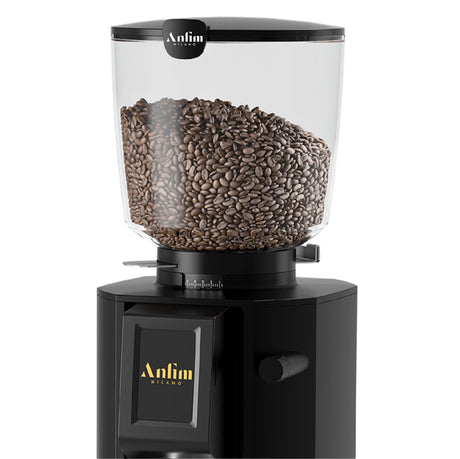 Black coffee grinder with glass container filled with coffee beans on a white background