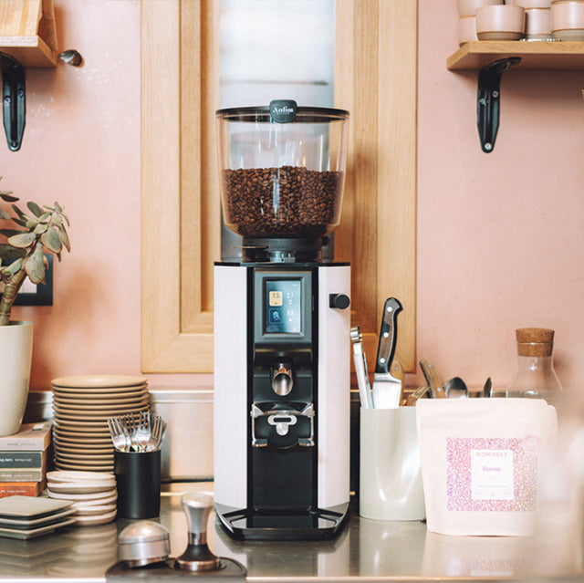 Coffee grinder on a kitchen counter with various items in the background
