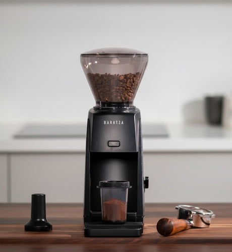 Baratza coffee grinder with ground coffee on a wooden surface