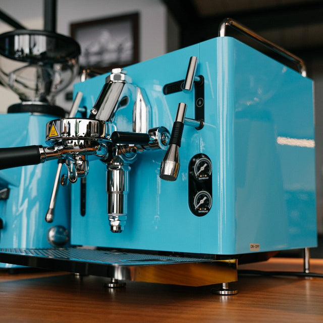 Blue espresso machine on a wooden surface with a blurred background