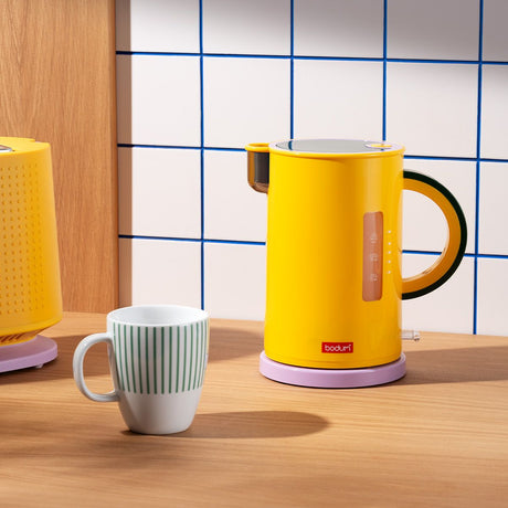 Yellow electric kettle and mug on a wooden surface with tiled wall background