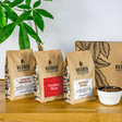 Redber Coffee Roasters packages on a wooden surface with a plant in the background