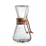 Clear glass coffee maker with a brown leather strap on a white background