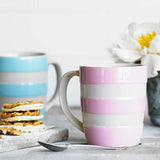 Colorful striped mugs on a table with a spoon and cookies.