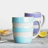 Blue and white striped mug on a wooden surface with lemons in the background