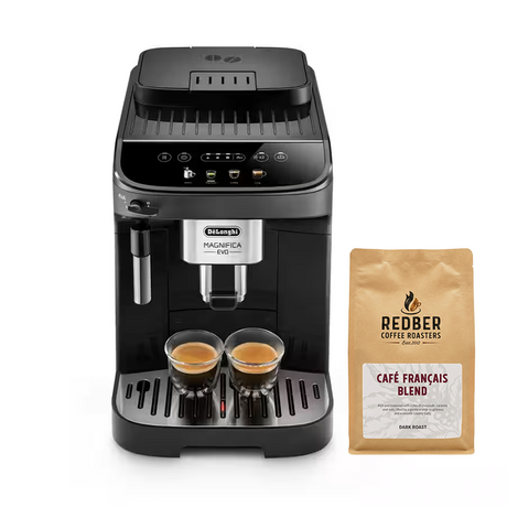 A De'Longhi Magnifica Evo coffee machine in black and silver, shown with two glasses of espresso on its drip tray next to a bag of Redber Coffee Roasters Café Français Blend dark roast coffee, on a white background.