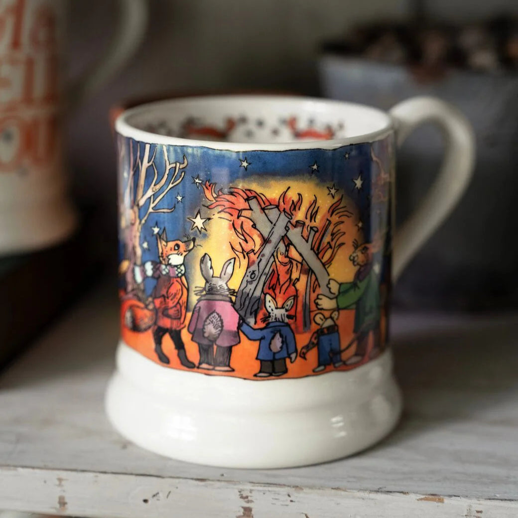 Mug with a colorful illustration of people around a campfire on a wooden surface.