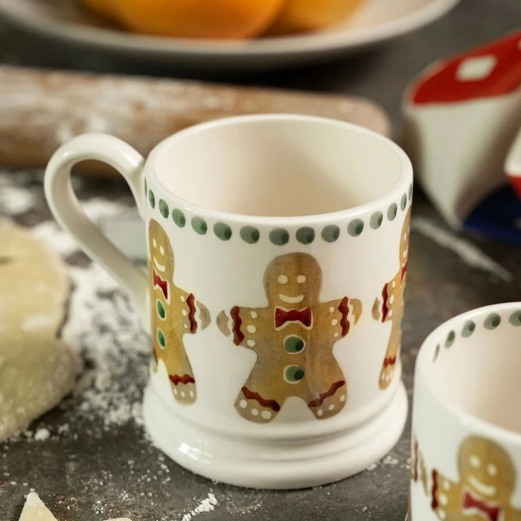 White mug with gingerbread men design on a surface with baking items in the background