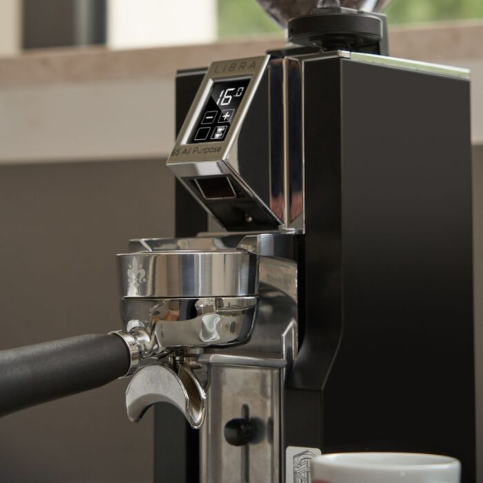 Close-up of an espresso machine with a digital display and a cup on a blurred background