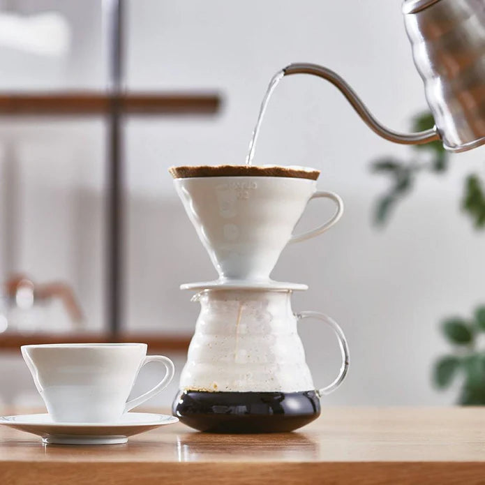 Coffee brewing process with a pour-over setup on a wooden table.